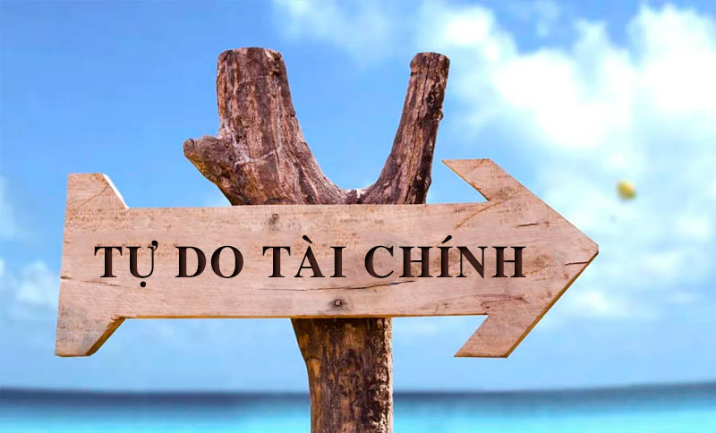 Tấm biển gỗ hình mũi tên chỉ sang phải với dòng chữ "Tự Do Tài Chính", nền là bầu trời xanh và biển.